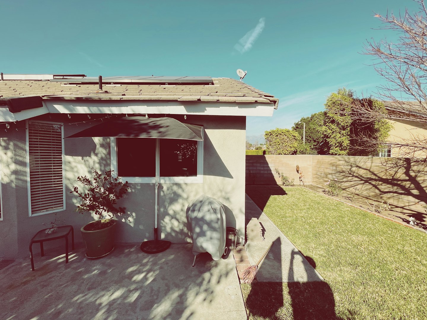 Solar panels sit on a residential roof above a patio.